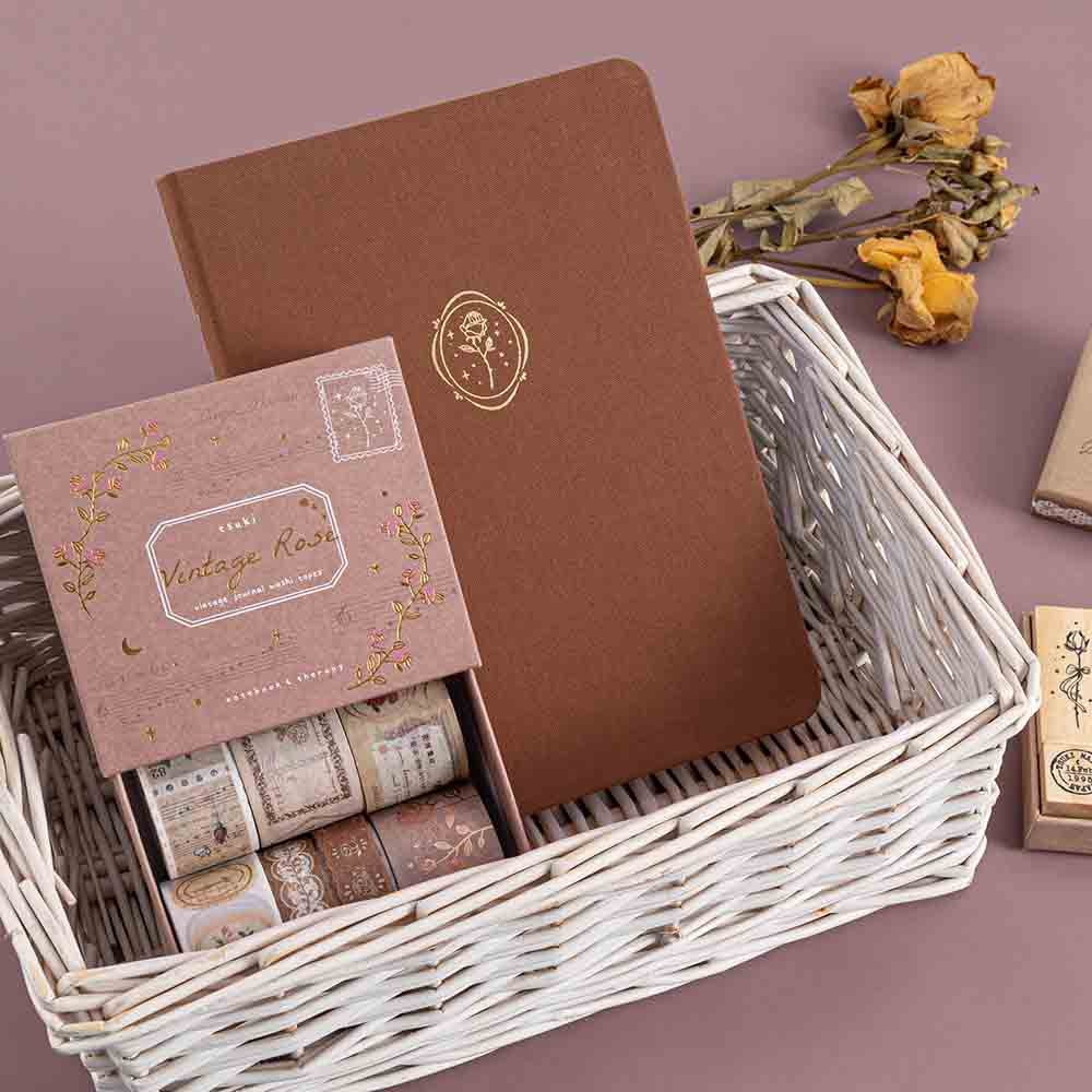 Tsuki ‘Vintage Rose’ Limited Edition Bullet Journal with Tsuki ‘Vintage Rose’ Washi Tape Set in basket with dried flowers and Tsuki ‘Vintage Rose’ Bullet Journal Stamp Set in mauve background