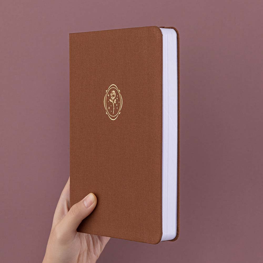 Tsuki ‘Vintage Rose’ Limited Edition Bullet Journal held in hand at spine angle in mauve background