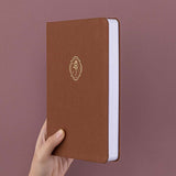 Tsuki ‘Vintage Rose’ Limited Edition Bullet Journal held in hand at spine angle in mauve background