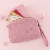 Tsuki ‘Sakura Journey’ Travel Pouch with travel essentials and Tsuki ‘Sakura Journey’ Limited Edition Travel Notebook inside with cherry blossoms on pink background