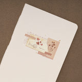 Vintage style collage with dried flowers and ripped paper printed on textured paper cover of a junk journal notebook