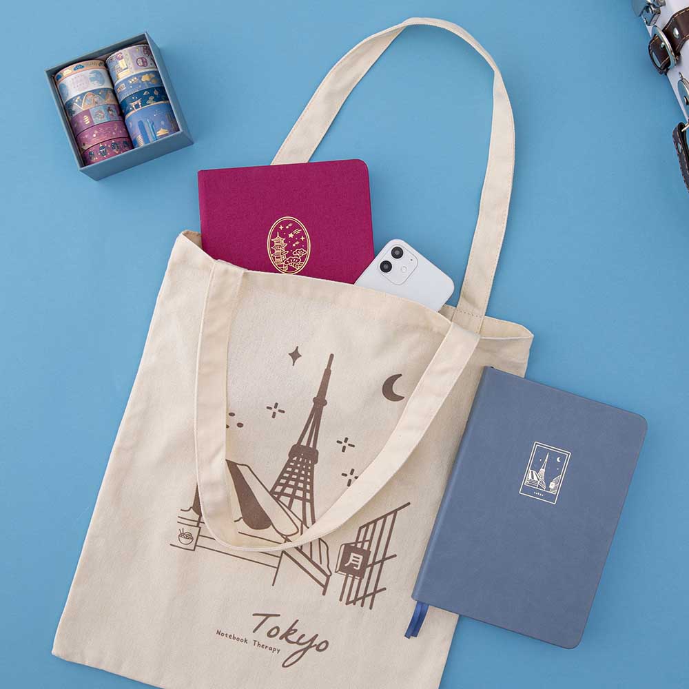 Kyoto notebook and iPhone in Tokyo tote bag and a Tokyo bullet journal on blue background