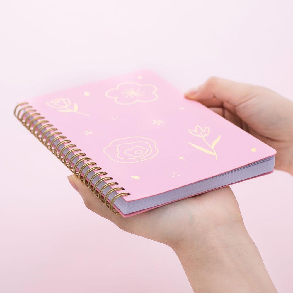 Tsuki sakura pink floral ringbound notebook held in hand at bottom angle in pink background