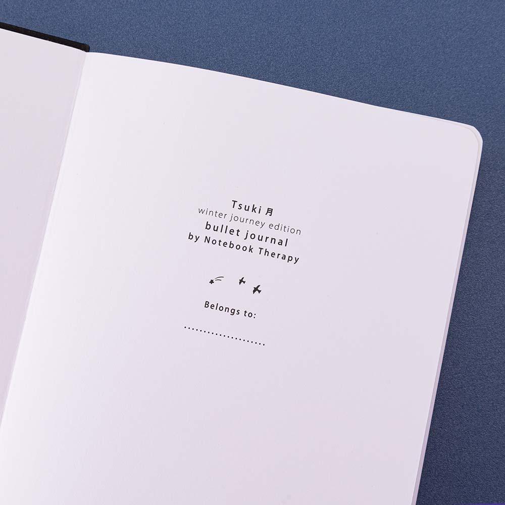Close up of the open front page of Tsuki ‘Winter Journey’ Limited Edition Bullet Journal on navy background