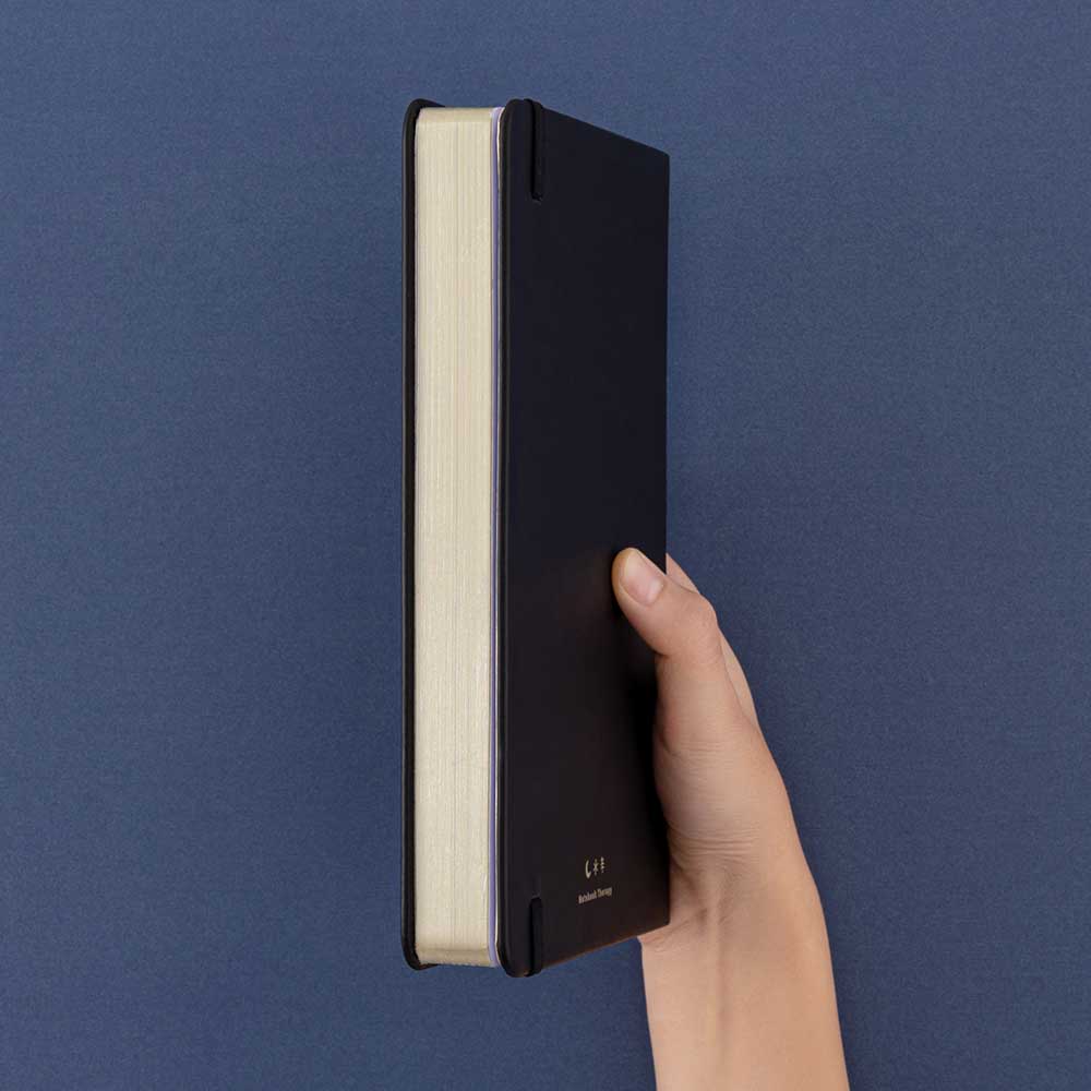 Tsuki ‘Winter Journey’ Limited Edition Bullet Journal held in hand at spine angle in navy background