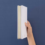 Tsuki Suzume’ Winter Limited Edition Bullet Journal held in hand at spine angle in navy background