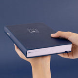 Tsuki ‘Winter Wishes’ Limited Edition Bullet Journal held in hands at an angle in navy background