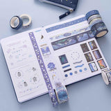 Tsuki ‘Dreams of Snow’ Holographic Washi Tape Set on open bullet journal spread with Tsuki ‘Dreams of Snow’ Pop-Up Pencil Case in Starry Night on light blue background