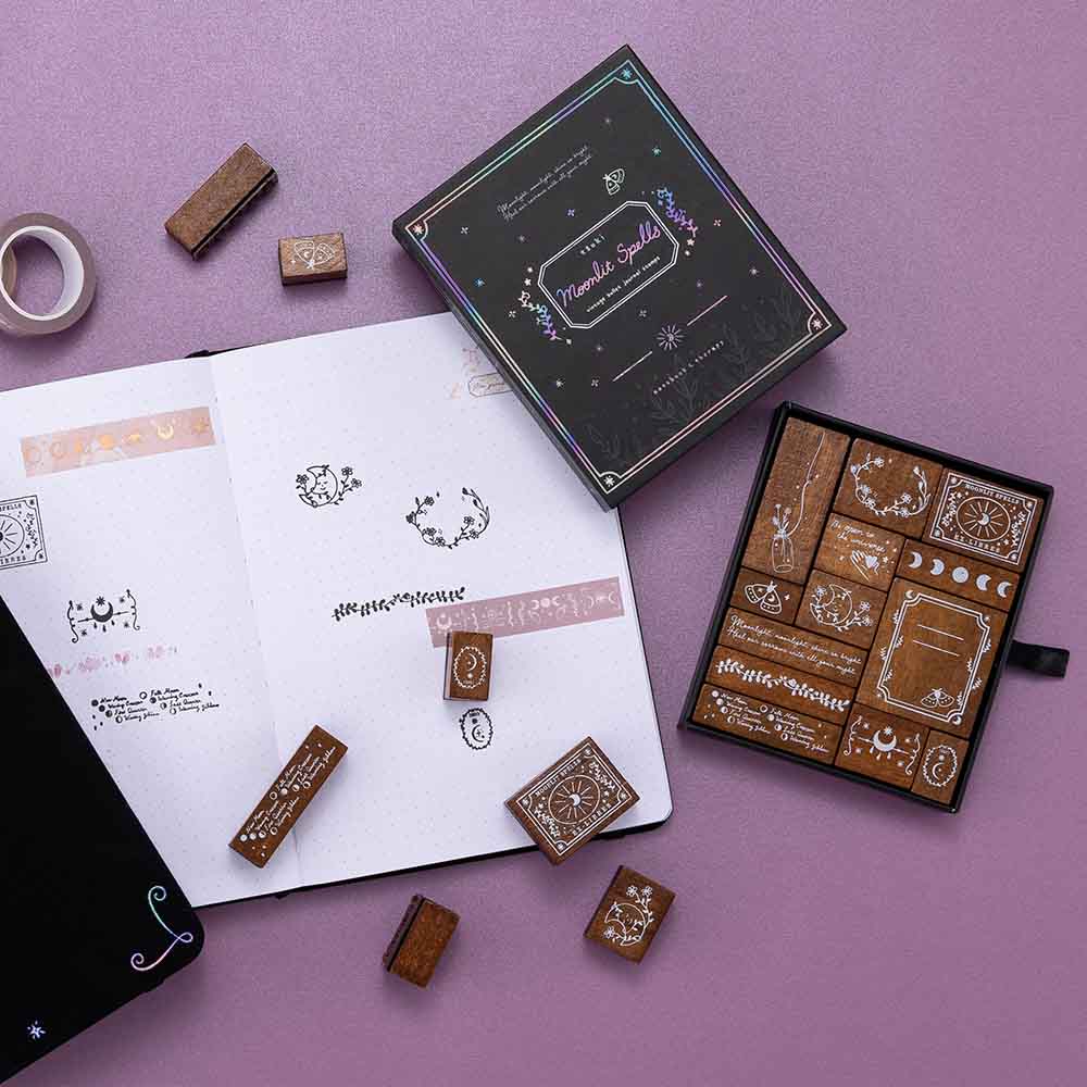 Tsuki ‘Moonlit Spells’ Bullet Journal Stamp Set with Tsuki ‘Moonlit Blush’ Washi Tapes on open bullet journal page with Tsuki ‘Moonlit Spell’ Limited Edition Holographic Bullet Journal on purple background