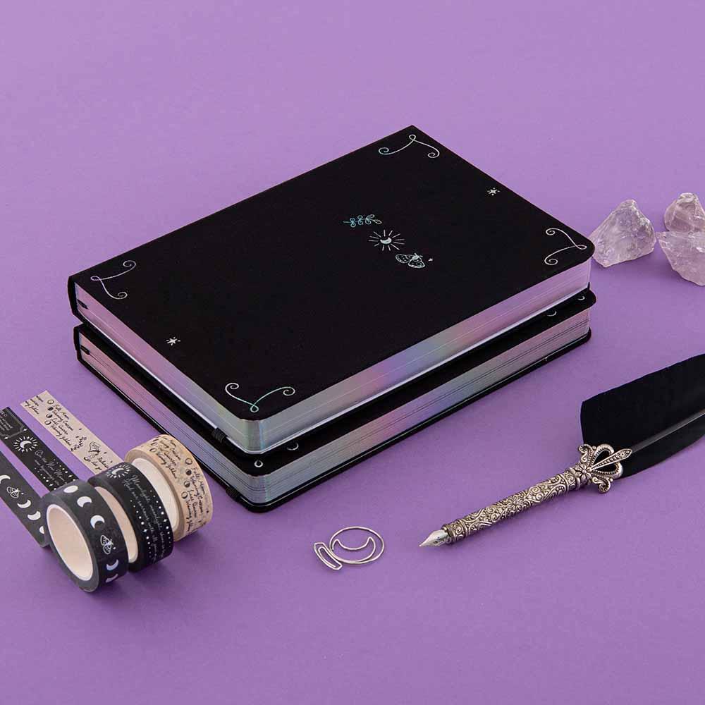Tsuki ‘Moonlit Spell’ Limited Edition Holographic Bullet Journals in white and black paper variations with free bookmark gift with Tsuki ‘Moonlit Spell’ Washi Tapes with amethyst stones and black feather quill on purple background