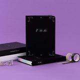 Tsuki ‘Moonlit Spell’ Limited Edition Holographic Bullet Journals in white and black paper variations with eco-friendly gift boxes with Tsuki ‘Moonlit Spell’ Washi Tapes with amethyst stones in purple background  Edit alt text