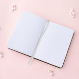 Open Tsuki Lunar Notes bullet journal flatlay image on pink background