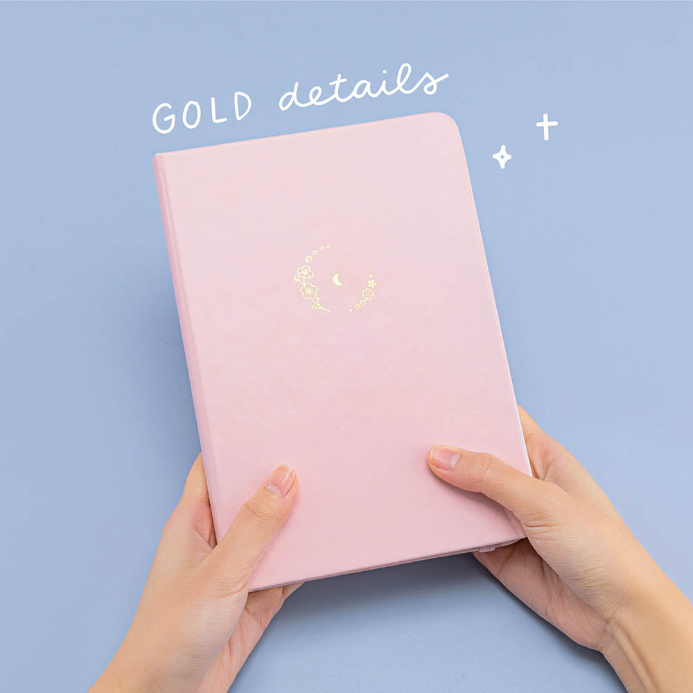 Tsuki ‘Lunar Blossom’ Limited Edition Bullet Journal with gold details held in hands in light blue background
