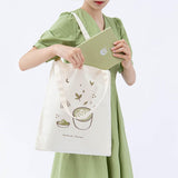 Tsuki ‘Matcha Matcha’ Tote Bag shown carried by model with Tsuki ‘Matcha Matcha’ Limited Edition Bullet Journal in light grey background