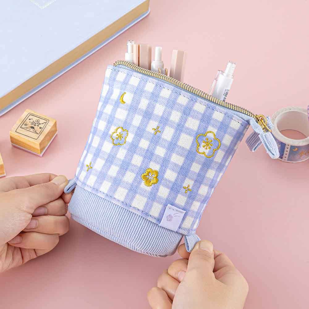 Tsuki ‘Sakura Journey’ Pop-Up Pencil Case with pens inside held in hands with Tsuki ‘Sakura Journey’ Washi Tape and Tsuki ‘Sakura Journey’ Bullet Journal Stamps and Tsuki ‘Sakura Journey’ Limited Edition Bullet Journal on light pink background