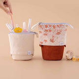 Tsuki ‘Maple Dreams’ Pop-Up Pencil cases in stone and maple with Tsuki ‘Maple Dreams’ Washi Tapes with pens held in hand in beige background