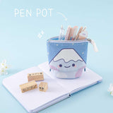 Tsuki ‘Four Seasons’ Fuji Pop-Up Pencil Case by Notebook Therapy x Milkkoyo which doubles as a pen pot with Tsuki ‘Four Seasons’ Bullet Journal Stamps on open bullet journal page spread with white flowers in light blue background