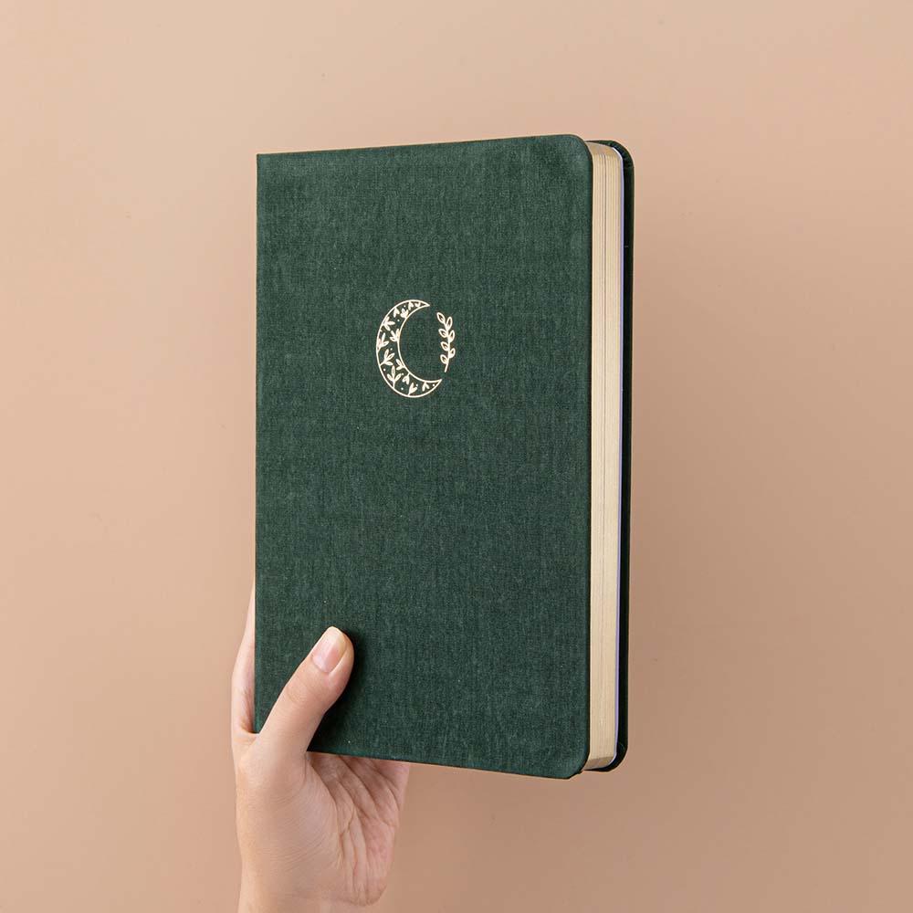 Tsuki ‘Midnight Garden’ Limited Edition Bullet Journal held in hand at spine angle in beige background