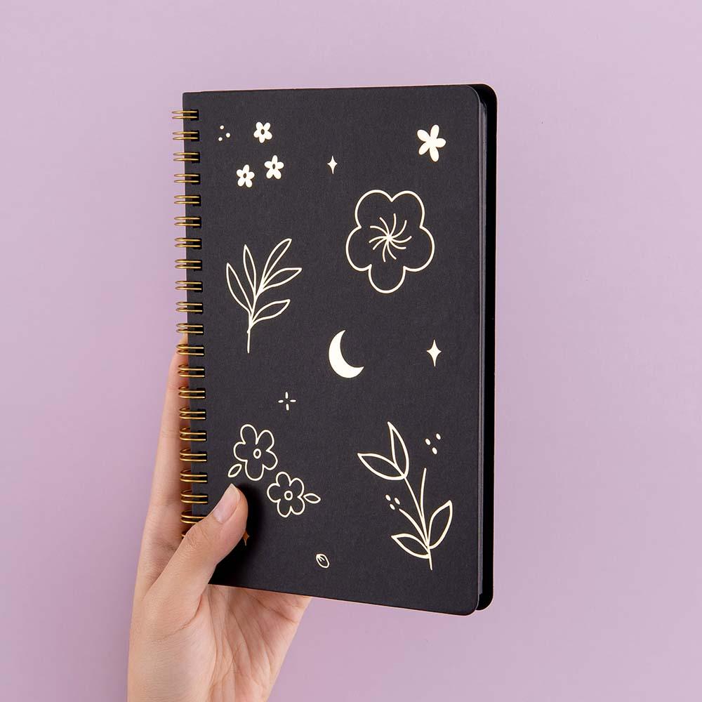 Tsuki Black Paper Ringbound Bullet Journal held in hand at spine angle in lilac background