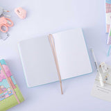Open page spread of Tsuki ‘Four Seasons: Autumn Edition’ Bullet Journal made with milkkoyo with Tsuki ‘Four Seasons: Summer Edition’ notebook with assorted stationery supplies on lilac background