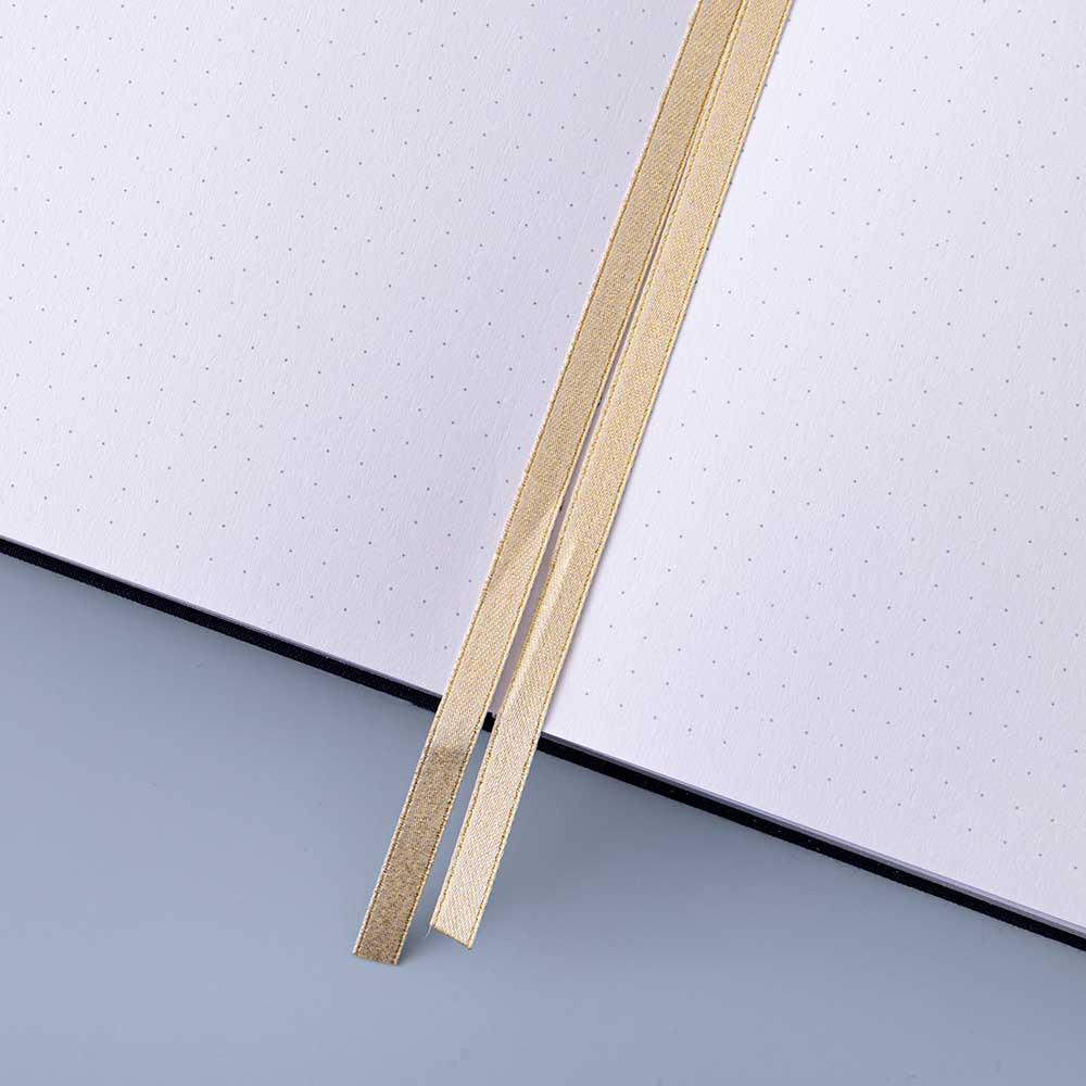 Close up of open pages and two bookmark ribbons of Tsuki ‘Cup of Galaxy’ Limited Edition Holographic Bullet Journal on light blue background