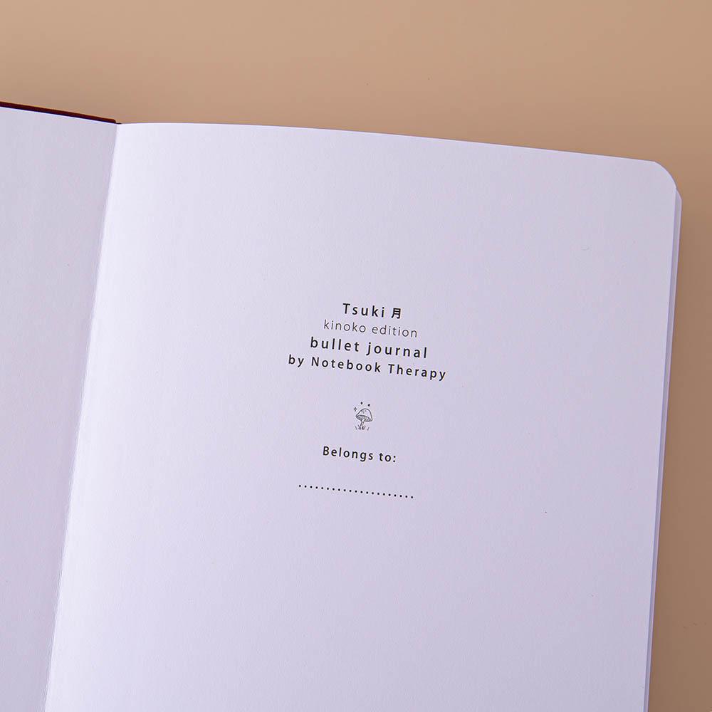 Close up of open front page of Tsuki ‘Kinoko’ Limited Edition Bullet Journal on beige background