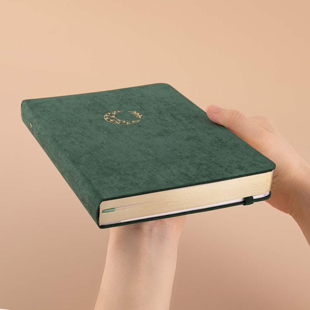 Tsuki ‘Midnight Garden’ Limited Edition Bullet Journal held in hands at an angle in beige background