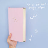 Tsuki ‘Lunar Blossom’ Limited Edition Bullet Journal held in hand at spine angle in light blue background