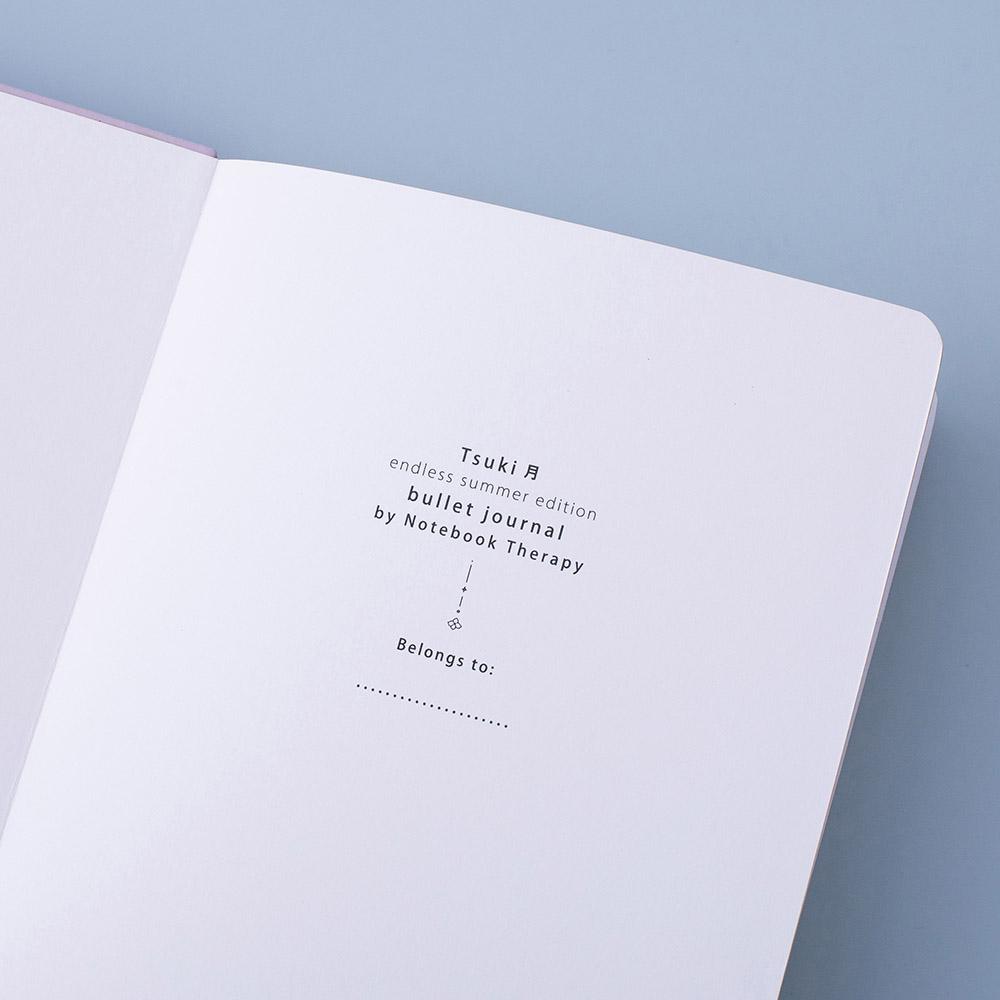 Close up of open front page of Tsuki Endless Summer Limited Edition Bullet Journal on light blue background