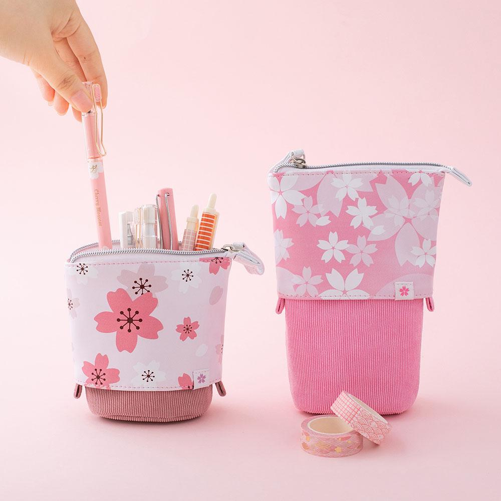 Tsuki 'Sakura Edition' Pop-Up Pencil Case in blush pink popped down with pens in and petal pink popped up with Tsuki 'Sakura Edition' Washi Tape Set in light pink background
