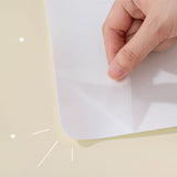 Close up of the back of Tsuki Reusable Weekly Planner with self-adhesive backing being removed on buttermilk beige background