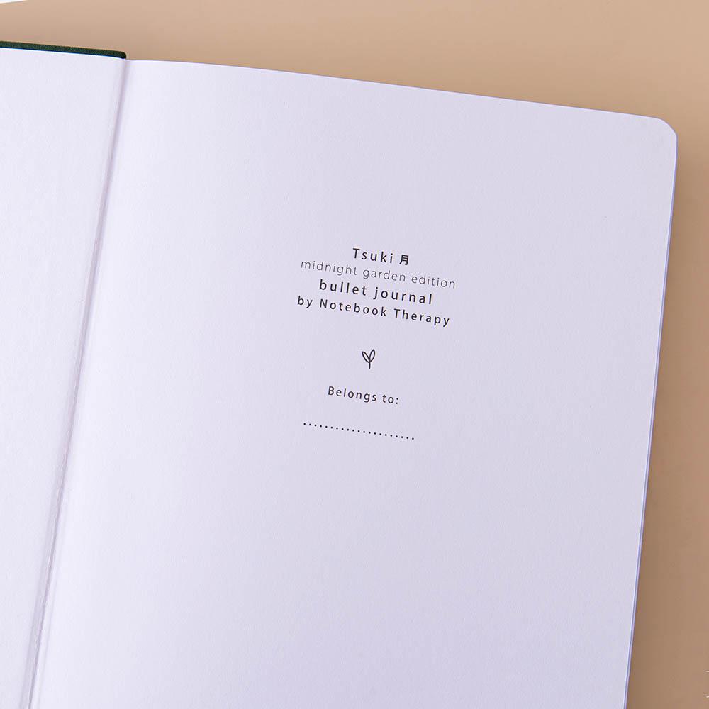 Close up of the open front page of Tsuki ‘Midnight Garden’ Limited Edition Bullet Journal on beige background