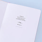 Close up of open front page of Tsuki ‘Lunar Blossom’ Limited Edition Bullet Journal on light blue background