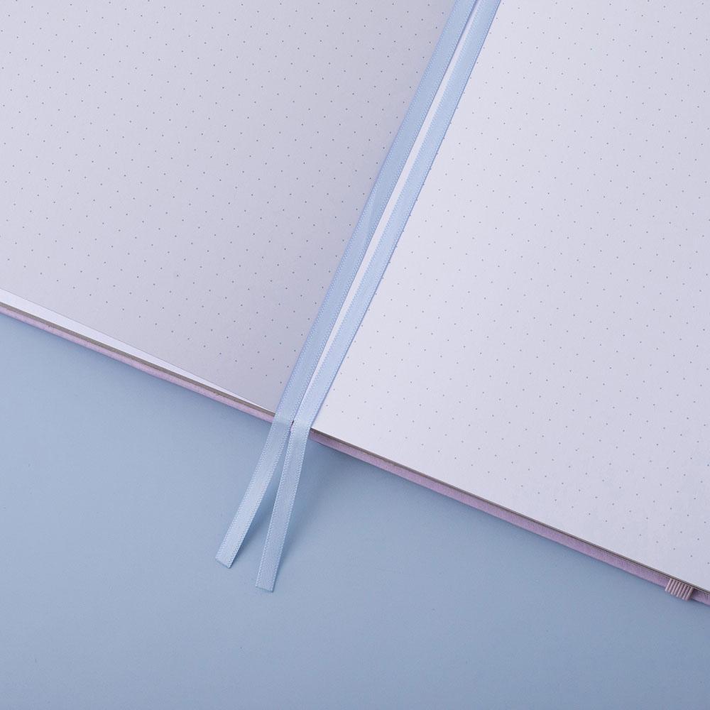 Close up of open pages of Tsuki Endless Summer Limited Edition Bullet Journal with two bookmark ribbons on light blue background