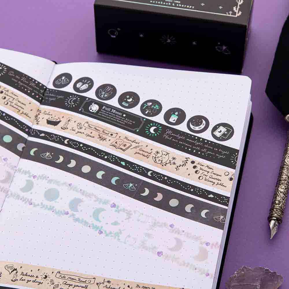 Close up of Tsuki ‘Moonlit Spell’ Washi Tapes rolled out on open Tsuki ‘Moonlit Spell’ Limited Edition Holographic Bullet Journal page with black feather quill on purple background