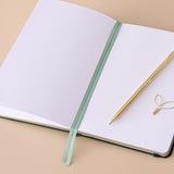 Close up of open page spread of Tsuki ‘Midnight Garden’ Limited Edition Bullet Journal with two bookmark ribbons on beige background