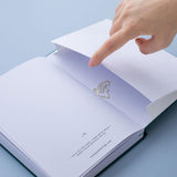 Sea green velvet Tsuki Dolphin Days bullet journal on open page with free dolphin gift on blue background