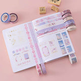 Tsuki ‘Sakura Journey’ Washi Tape Set rolled out on open Tsuki ‘Lunar Blossom’ Limited Edition Bullet Journal with Tsuki ‘Sakura Blossom’ Bullet Journal Stamp Set on light pink background
