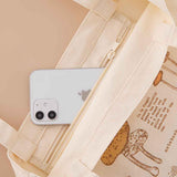 Close up of zippable inside pocket of Tsuki ‘Vintage Kinoko’ Tote Bag with mobile phone inside on beige background