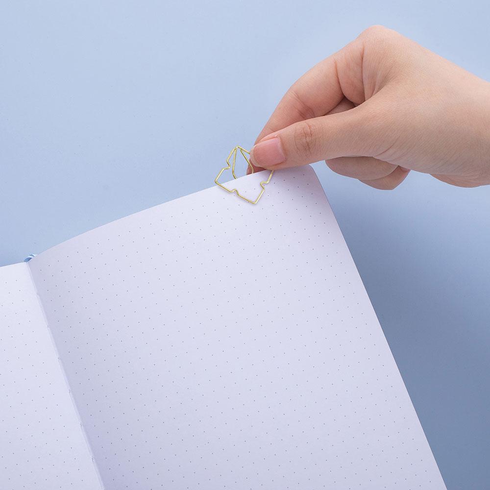 Close up of open page of Tsuki Endless Summer Limited Edition Bullet Journal with free gift held in hand on light blue background