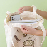Close up of the inside of Tsuki ‘Matcha Matcha’ Tote Bag held in hands with laptop and mobile phone with inside zippable pocket in matcha green background