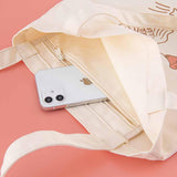 Close up of Tsuki ‘Moonflower’ Limited Edition Tote Bag with phone inside on coral pink background