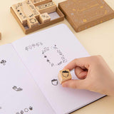 Tsuki ‘Maple Dreams’ Bullet Journal Stamp Set being demonstrated on open bullet journal page with stamp held in hand on cream background