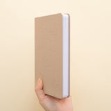 Hand holding beige bullet journal with constellations design in rose gold foil