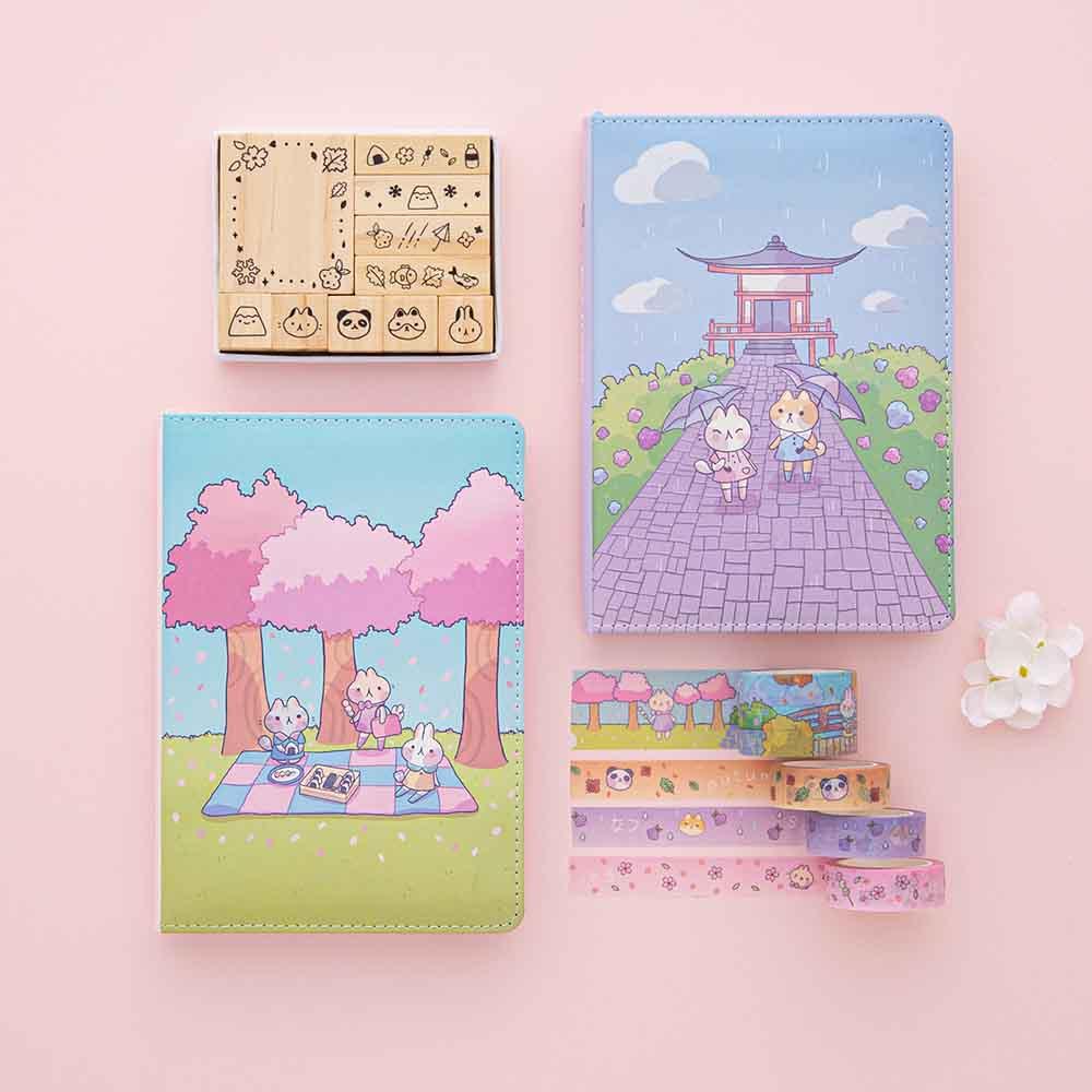 Tsuki ‘Four Seasons’ Bullet Journal Stamp Set by Notebook Therapy x Milkkoyo with Tsuki ‘Four Seasons’ Washi Tapes and Tsuki ‘Four Seasons: Spring Edition’ Bullet Journal and Tsuki ‘Four Seasons: Summer Edition’ Bullet Journal with white flower on petal pink background