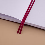 Close up of open page spread of Tsuki ‘Kinoko’ Limited Edition Bullet Journal with two bookmark ribbons on beige background
