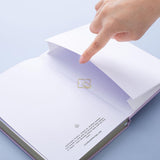 Close up of open back page pocket of Tsuki Endless Summer Limited Edition Bullet Journal with free gift on light blue background