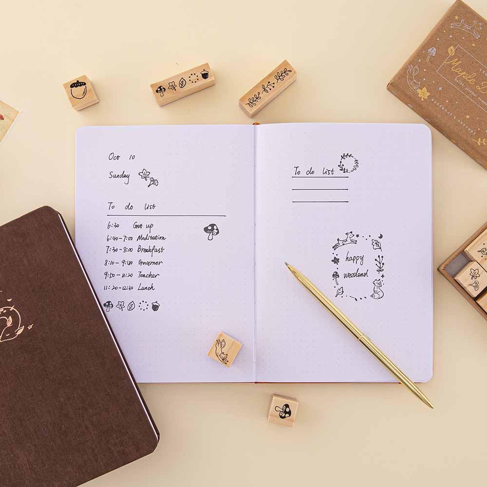 Tsuki ‘Maple Dreams’ Bullet Journal Stamp Set demonstrated on open bullet journal page spread with Tsuki ‘Nara’ Limited Edition Bullet Journal and gold pen on cream background