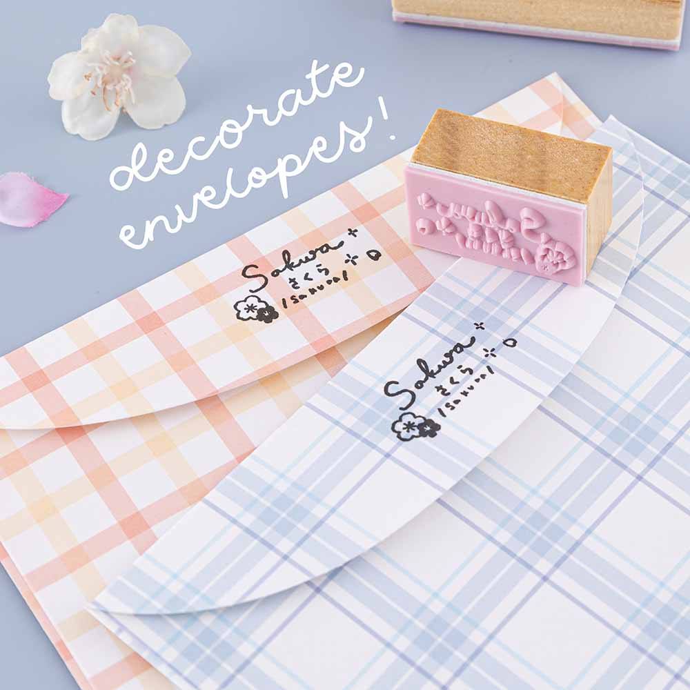 Close up of Tsuki ‘Sakura Journey’ Bullet Journal Stamp to decorate envelopes with on blue and orange gingham envelopes with cherry blossoms on light blue background