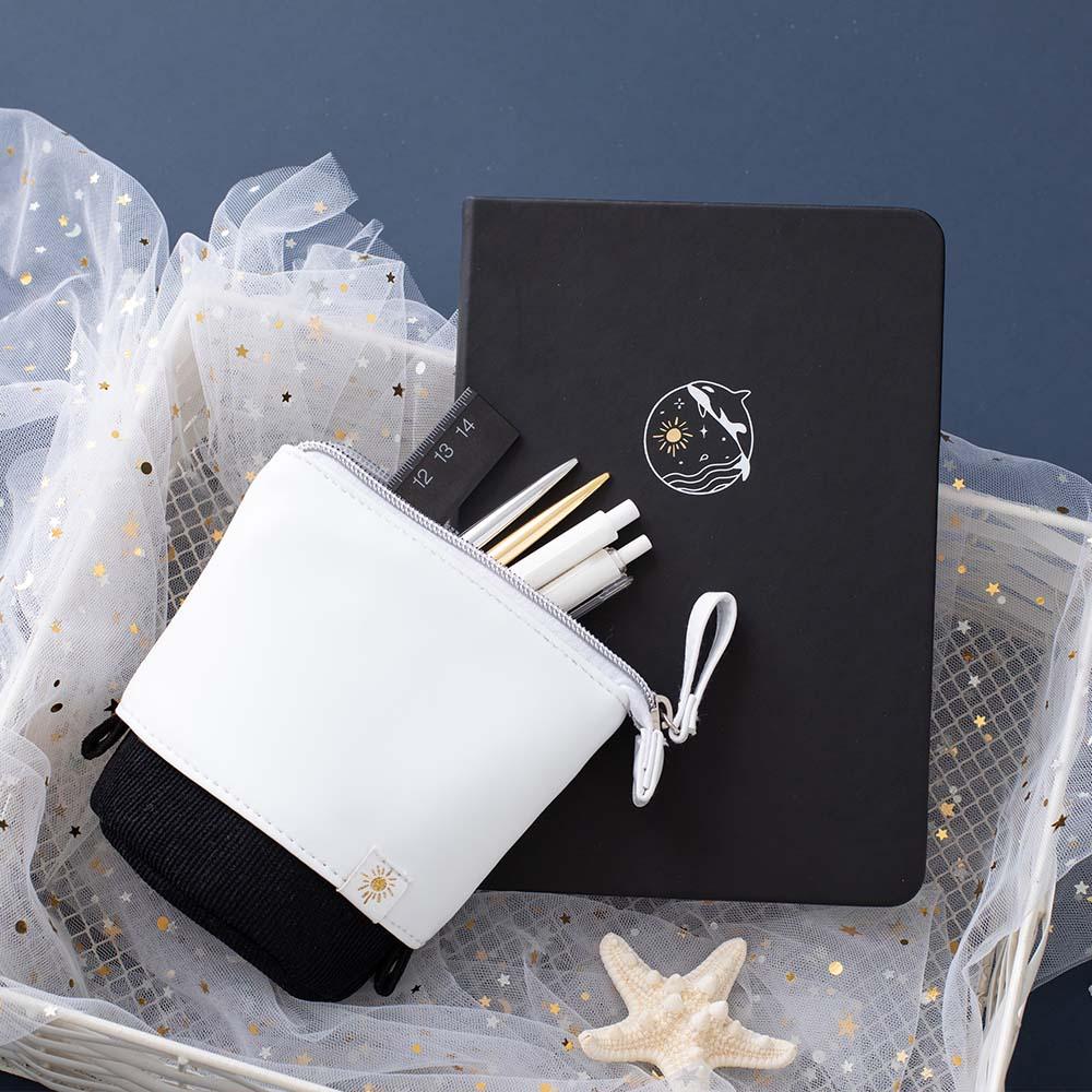 Tsuki Ocean Edition pop up standing pencil case in Orca Black with deep black vegan leather Playful Orca limited edition notebook in basket with pens and starfish in dark blue background